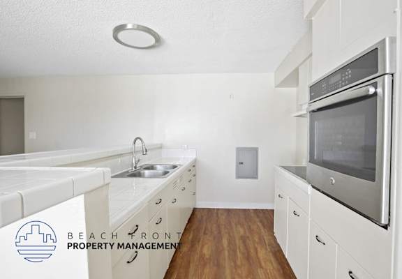 A kitchen with white cabinets and a stainless steel oven.