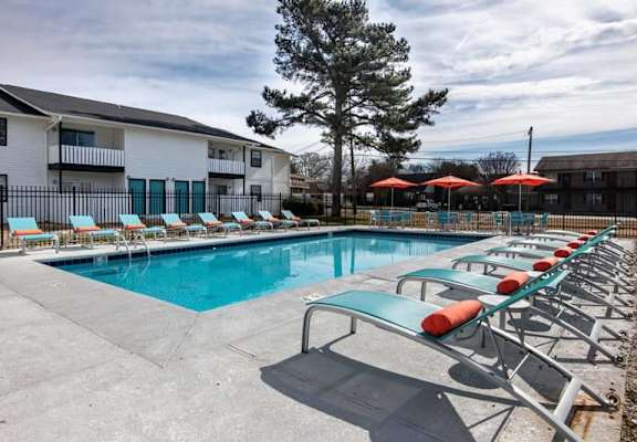 a pool with chairs and umbrellas next to a building at Cleo Apartments, Athens