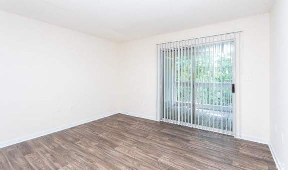 A room with a sliding glass door and wooden flooring.