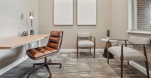 A room with a brown chair and a white table.