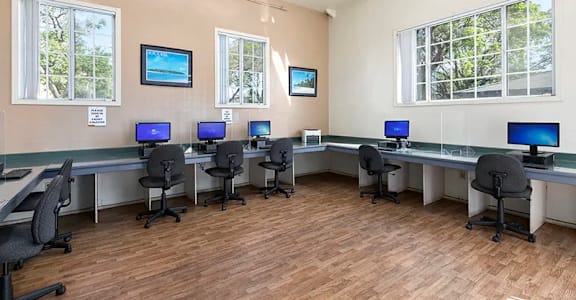 a classroom with desks and chairs with computer monitors