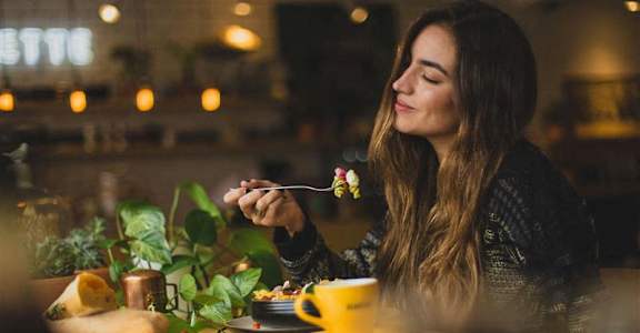 a woman sitting at a table with a plate of food