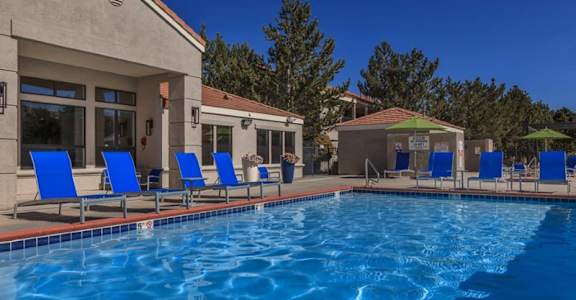 A pool with blue chairs and a building in the background.