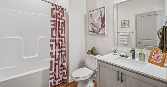 A bathroom with a toilet, sink, and shower curtain.