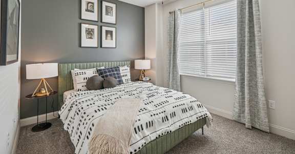 A bedroom with a bed, two lamps, and a ceiling fan.