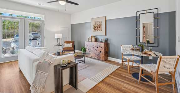 A living room with a white couch, a wooden coffee table, and a dining table set up.