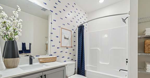 A white toilet sits in a bathroom with a blue and white wallpaper.