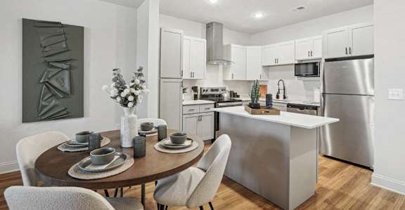 A modern kitchen with a dining table set for two.