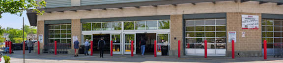 A Costco store with people standing outside.