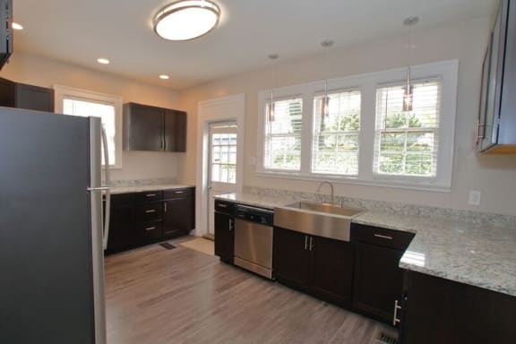 a kitchen with dark cabinets and a stainless steel sink
