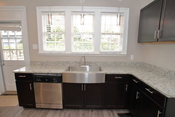 a kitchen with dark cabinets and a stainless steel sink