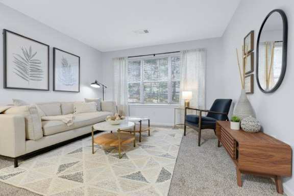 A living room with a white sofa, a coffee table, a side table, and a large mirror.
