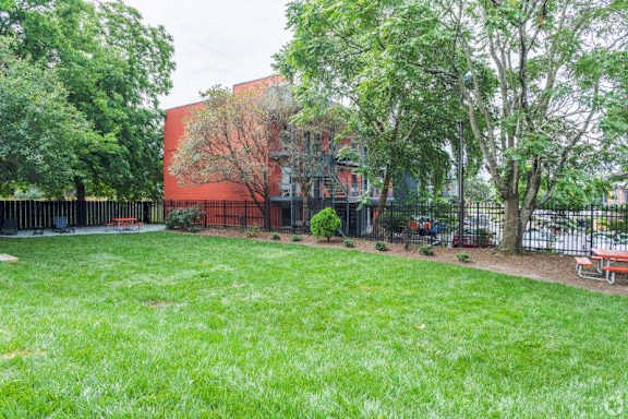 a yard in front of a building with trees and benches at Capital Flats & Magnolia Square Apartments, Raleigh, 27601