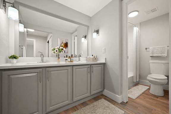 A bathroom with a white toilet and grey cabinets. at The Lex At Lowry, Denver, 80224