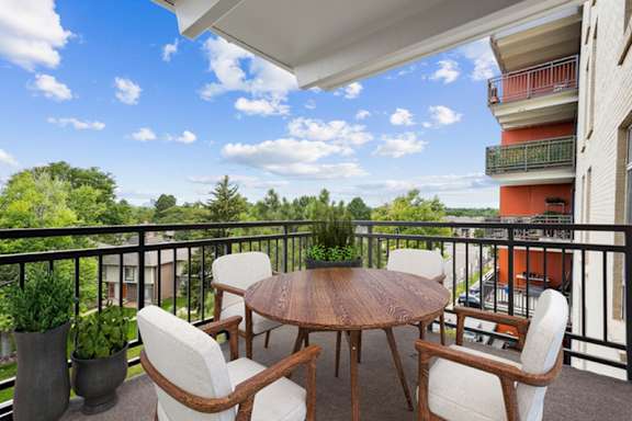 A balcony with a table and chairs overlooking a building and trees. at The Lex At Lowry, Denver, Colorado
