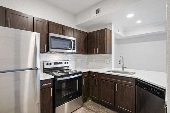 a kitchen with wooden cabinets and stainless steel appliances at The Legends at Eagle Mountain Lake, Fort Worth, 76179