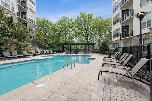 A swimming pool surrounded by lounge chairs and trees.