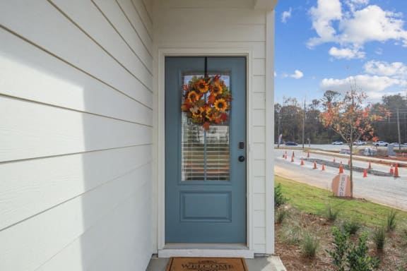 a blue door on a white house with a wreath on it