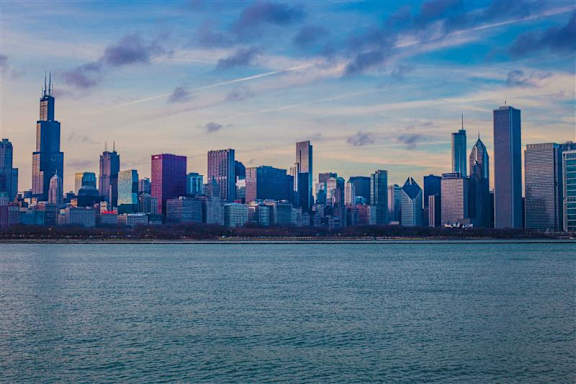 A city skyline with tall buildings and a body of water in the foreground.