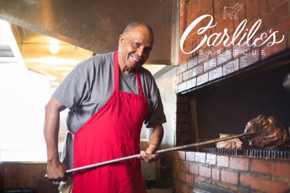 a man in a red apron cooking food on a grill
