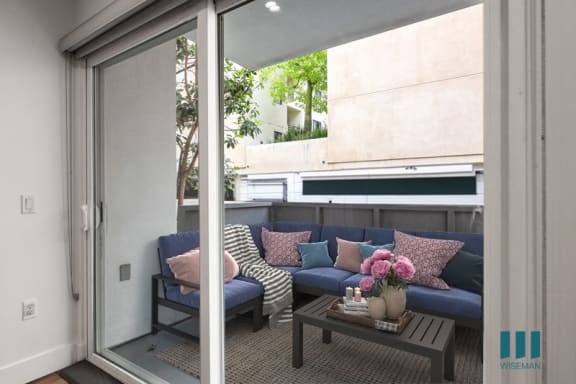 a balcony with a couch and a table with a vase of flowers