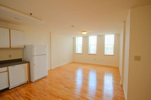 open layout living room that is attached to kitchen; white walls and hardwood floors