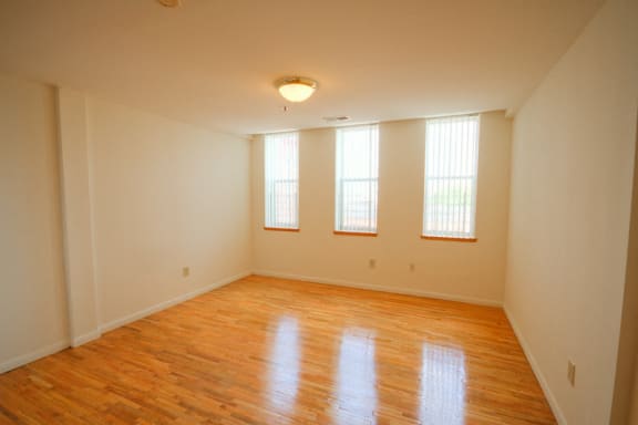 living room with 3 windows, hardwood floors and white walls