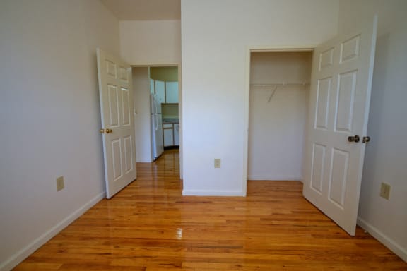 bedroom with hardwood floors, white walls and closet