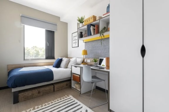 a bedroom with a bed and a desk with a computer