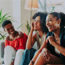 Three people are sitting on a couch, laughing and enjoying each other's company.
