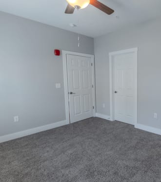 a bedroom with two doors and a carpeted floor and a ceiling fan
