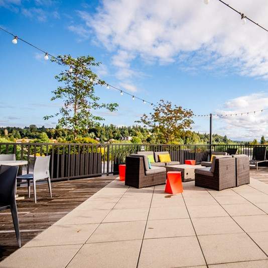 A patio with a table, chairs, and a string of lights.