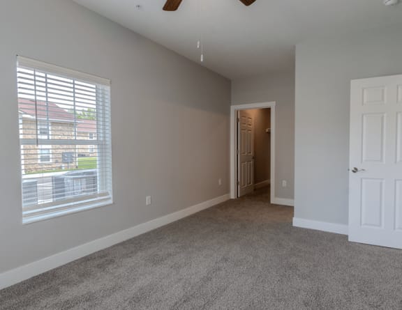 an empty living room with a large window and a white door
