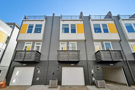 A row of modern townhouses with balconies and garages.