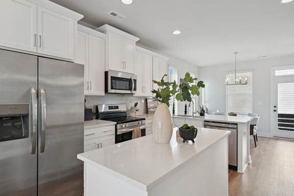 A modern kitchen with a stainless steel refrigerator and white cabinets.