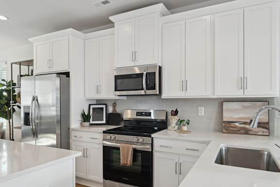 A modern kitchen with white cabinets and stainless steel appliances.