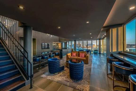 the lobby of a hotel with tables and chairs and a staircase