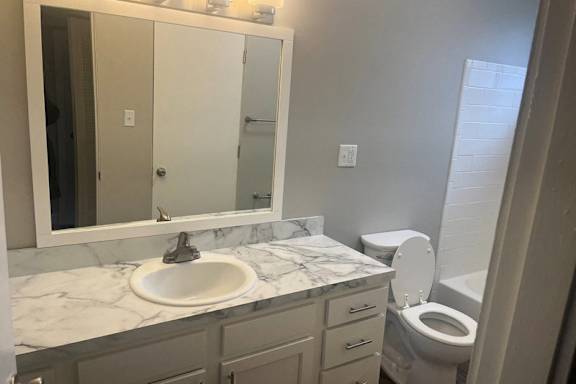 A bathroom with a marble countertop and a white toilet.
