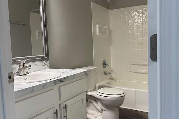 A white toilet sits in a bathroom next to a bathtub.