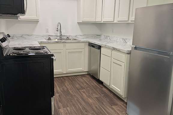 A kitchen with a black stove top oven and a stainless steel refrigerator.