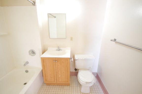 bathroom with light wooden cabinet, white tile floor and white walls
