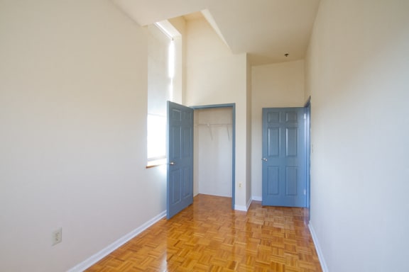 Bedroom with hardwood floors, white walls, and closet with blue doors