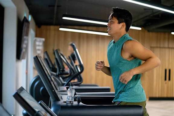 A man is running on a treadmill in a gym.