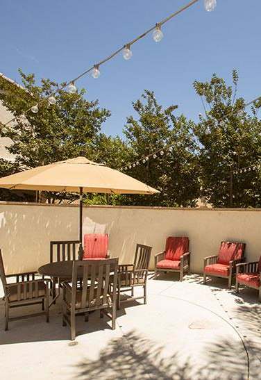 a patio with blue chairs and an umbrella