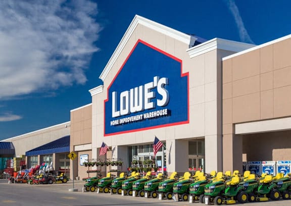 A Lowe's Home Improvement Warehouse store with lawn mowers in front.
