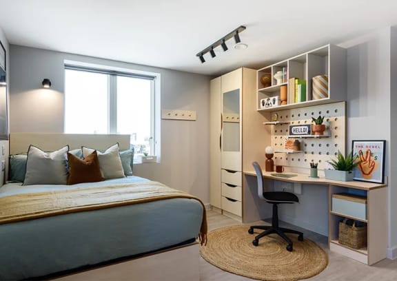a bedroom with a bed and a kitchen in the background