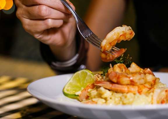 A person is eating shrimp with a fork.