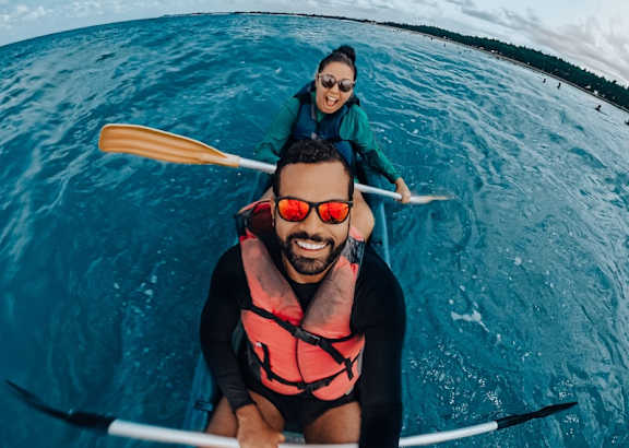 A man and a woman are kayaking in a blue body of water.