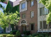Thumbnail 1 of 6 - a brick house with a tree and bushes in front of it
