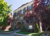 Thumbnail 1 of 4 - a brick building with a tree in front of it
